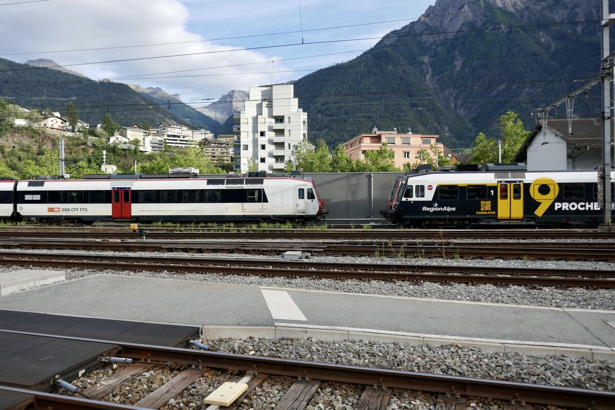 Der RBDe 560 221 der SBB und der ABt 954 von RegionAlps mit Kanal 9 Vollwerbung am 8.8.23 beim Bahnhof Brig.